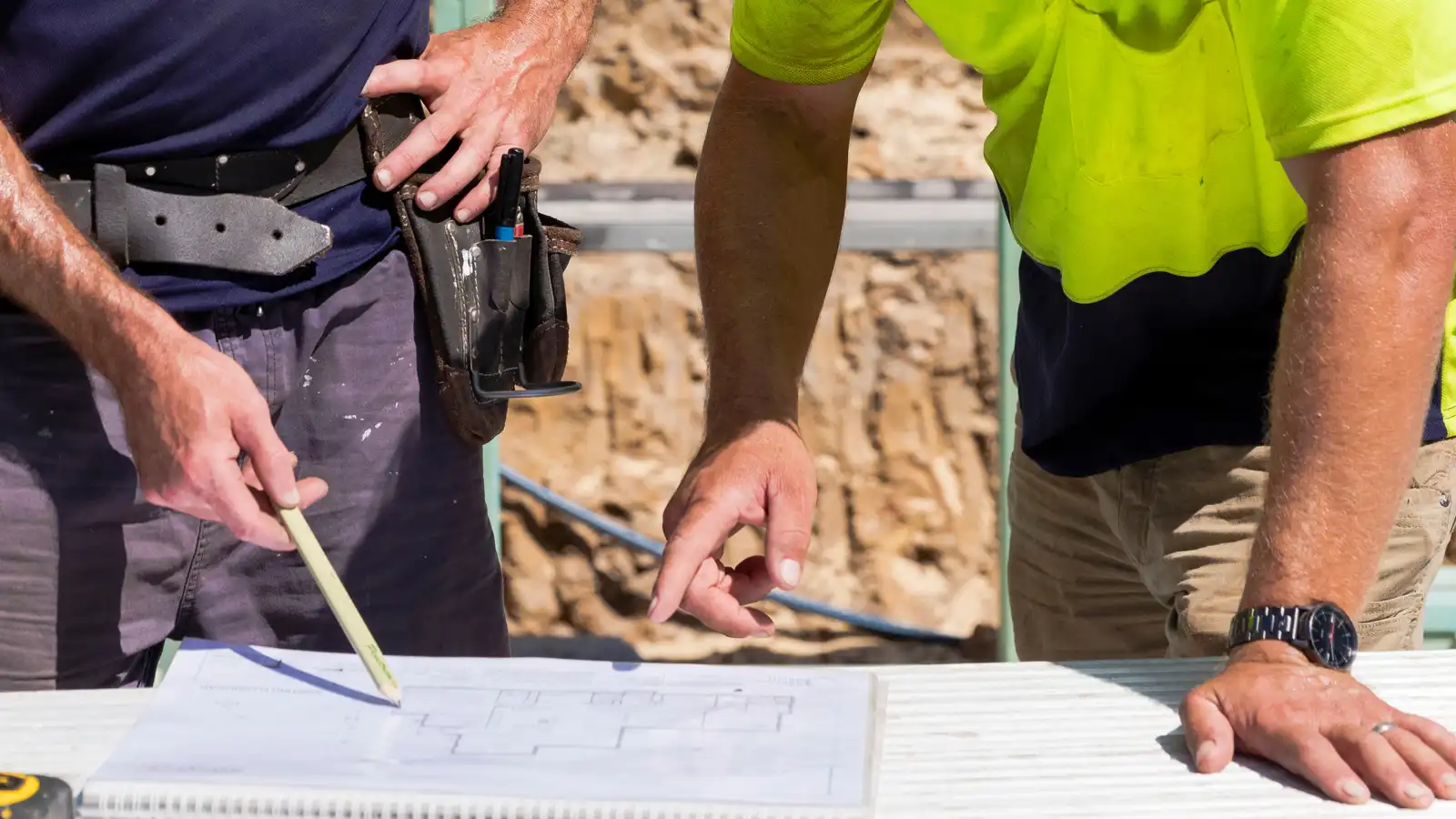Two tradesmen reviewing building plans on site, representing the ATO’s increased focus on tradies and professional services.