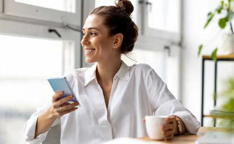Holmans Sunshine Coast client communicating via mobile phone while working at her desk.